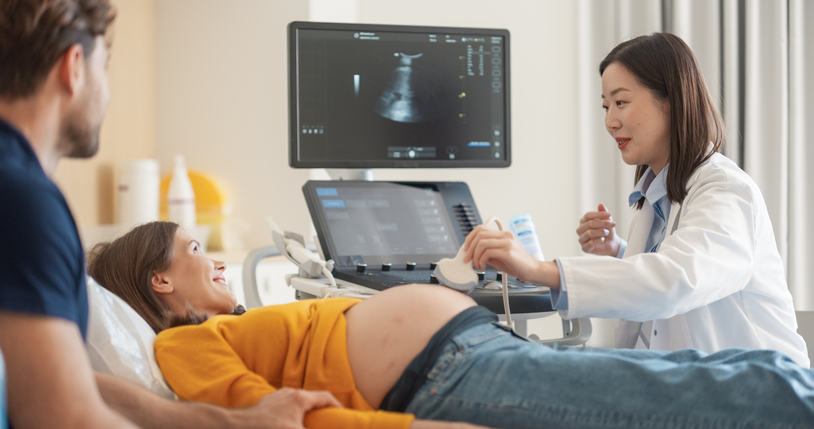 Sonographer performing test on pregnant woman.