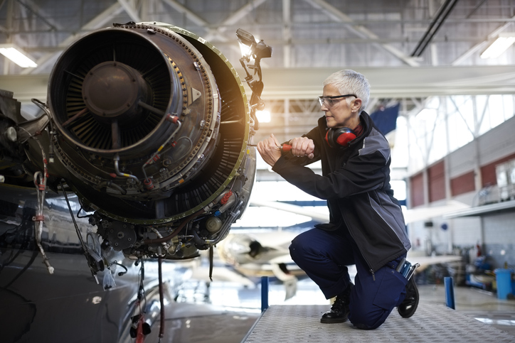 Female aircraft mechanic repairing a jet engine.