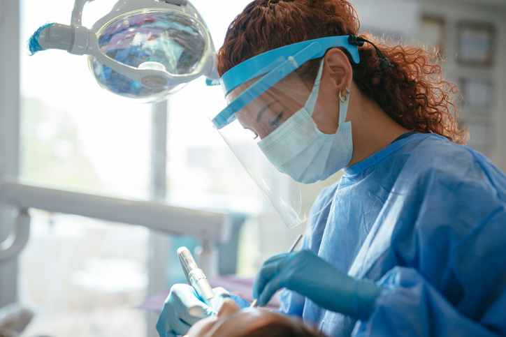Dental hygienist cleaning teeth of a patient.