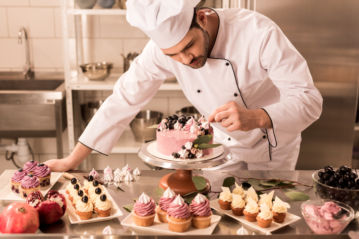 Pastry chef decorating a cake.